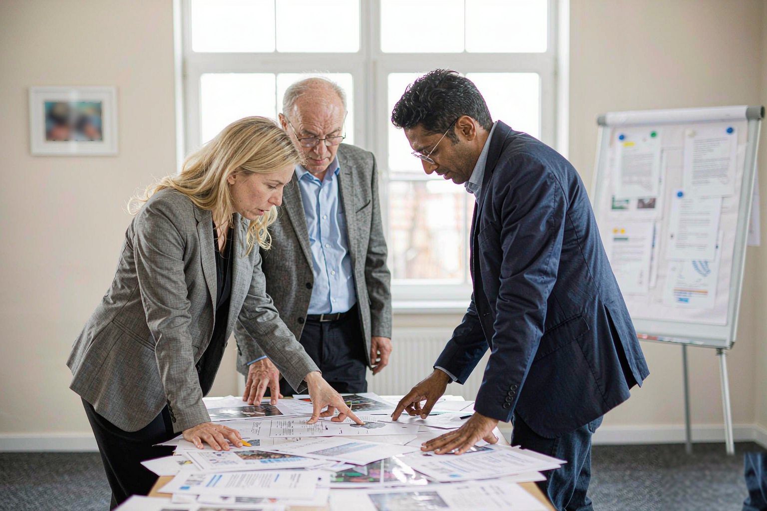 Small team reviewing printed findings around a meeting table